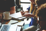 Mehrere Menschen während eines Meetings am Schreibtisch